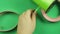 Woman scissors cut green ribbon on green background.