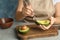 Woman scooping avocado with spoon at table