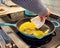Woman scrambling eggs using a piece of a plastic plate as a spatula