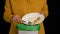 Woman scraping with a plate a chicken leg, rice, green peas into garbage bin