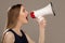 Woman scream in a megaphone. Gray background