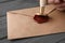 Woman sealing envelope at black wooden table, closeup