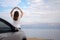 Woman seated on the engine hood of a rented car on a road trip in israel