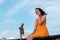 Woman seated on a pier in a tropical location using his smartphone and smiling. Sky with clouds as background