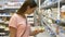 Woman selecting dairy food in fridge at grocery department of shopping mall