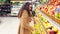 Woman selecting fresh red apples in grocery store produce department and putting it in plastic bag. Young pretty girl is