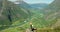 Woman, selfie stick and hiker on mountain, travel influencer and social media post on cliff. Female person, relaxing and