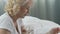 Woman of senior age praying at her bed, eyes closed, smiling, gratitude to God