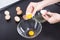 Woman separate egs in glass bowl on black table