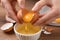 Woman separating egg yolk from white over bowl at wooden table, closeup