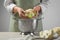 Woman separating fresh cauliflower cabbage above colander at wooden table, closeup