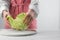 Woman separating leaf from fresh savoy cabbage at white marble table, closeup