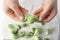 Woman separating leaves from fresh brussel sprouts at white table, closeup