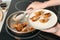 Woman serving freshly cooked delicious gyoza on plate in kitchen, closeup