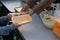 Woman serving jacket potato and its toppings into a take away lunch box.