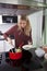 Woman serving pasta in bowl at kitchen counter