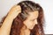 Woman setting back right side of hair to show graying roots on white background. Regrown roots which are in need of