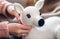 Woman sewing crochet white deer. Cute handmade toy. Finished process of japanese amigurumi