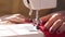 Woman sewing with modern sewing machine. A hand supporting a fleece cloth while sewing on a machine. red fabric. Woman`s