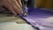 A woman sews a purple cloth on a sewing machine