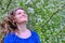 Woman shakes her hair shaking off white dandelion seeds