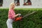 Woman shaping bushes with petrol hedge trimmer