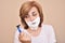 Woman with shaving foam on her face holding and looking sadly at a razor
