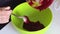 A woman shifts cranberry puree from one container to another. For the preparation of marshmallow.