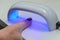 Woman shines with ultraviolet lamp on nails after manicure for nail polish to harden