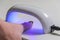 Woman shines with ultraviolet lamp on nails after manicure for nail polish to harden