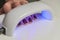 Woman shines with ultraviolet lamp on nails after manicure for nail polish to harden