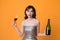Woman in shining dress with alcohol on yellow background
