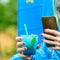 Woman shooting photo of cold blue cocktail in glass, outdoors. C