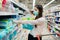 Woman shopper with mask and gloves panic buying and hoarding disposable diapers.Preparing for pathogen virus pandemic quarantine.