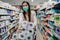 Woman shopper with mask and gloves panic buying and hoarding toilette paper in supply store.Preparing for pathogen virus pandemic