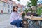 Woman shopping choosing pot with plant in store, on an outdoor rack