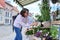 Woman shopping choosing pot with plant in store, on an outdoor rack