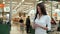 Woman shopping food in supermarket background. Close up view girl buy products using digital gadget in store. Hipster at