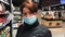Woman shopping a supermarket, a buyer in a medical mask chooses useful products to maintain health during a pandemic due