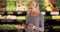 Woman shopping at supermarket, checking nutrition facts of product on phone