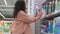 woman is shopping in supermarket, choosing cleaning products for home cleanup