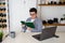 Woman with short black hair in glasses sits attentively at table, making notes in notebook. Planning, budgeting