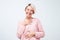 Woman with short dyed hair wearing pink sweater smiling broadly and keeping hand on her heart