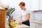 Woman with short ginger hair slicing banana for muesli breakfast in the kitchen
