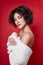 woman with short hair cut in white sweater on red background. Perfect girl with wet tousled dark hair and bright makeup,
