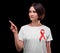 A woman with short hair and red ribbon pointing at something on a black background. Support people with AIDS. Health