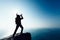 Woman shouting with loudspeaker on windy sunrise coast cliff edge