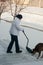 Woman shoveling snow with family dog