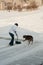 Woman shoveling snow with family dog