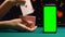 Woman showing ace of hearts near green screen smartphone, online poker app